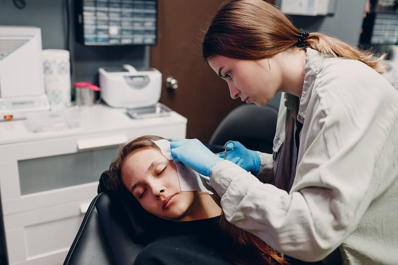Young woman doing ear piercing at beauty studio salon.
