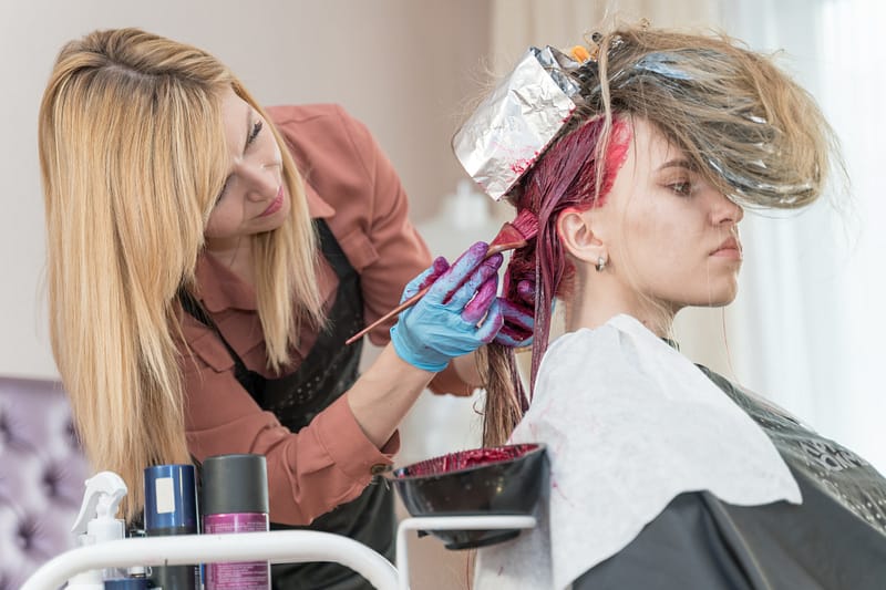hairdresser makes hair coloring to young girl